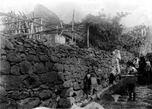 Barn som bærer ulike kurvtyper, ved steinmur - desc. - c. 1900